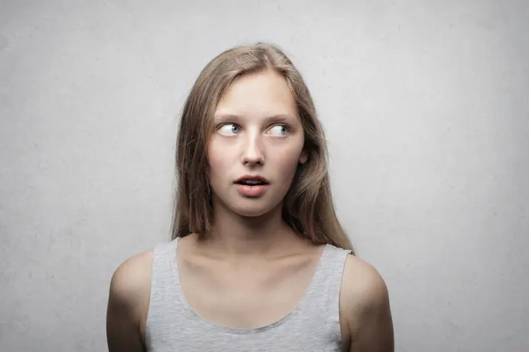 Young woman looking sideways with a curious expression in a studio portrait.