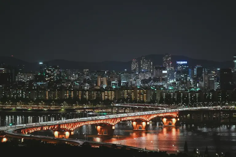a bridge over a river with a city in the background
