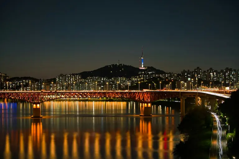 a bridge over a body of water with a city in the background