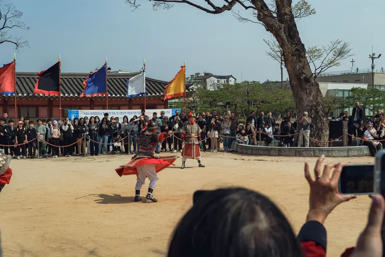 Vibrant display of traditional Korean martial arts outdoors in Seoul with spectators watching.