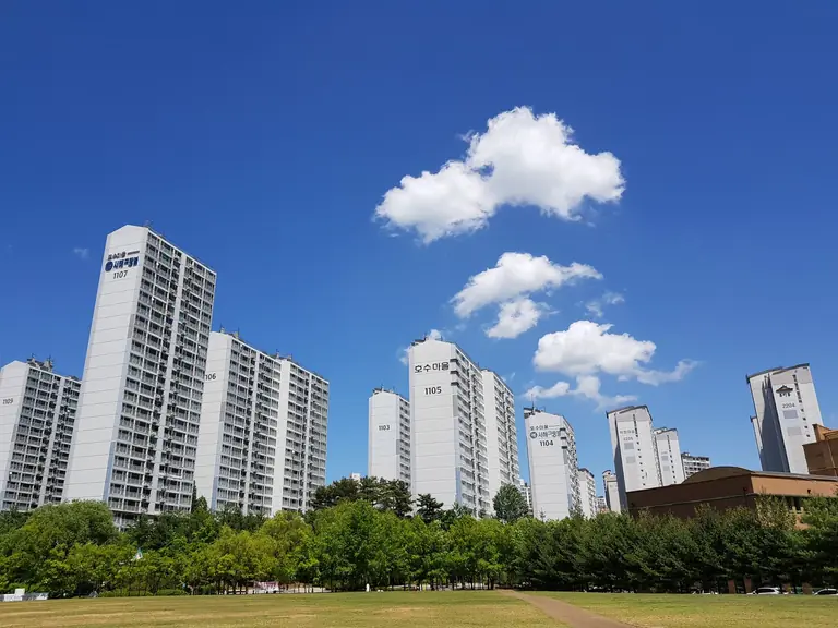 Skyline of high-rise apartments in Yongin with clear blue sky and clouds.