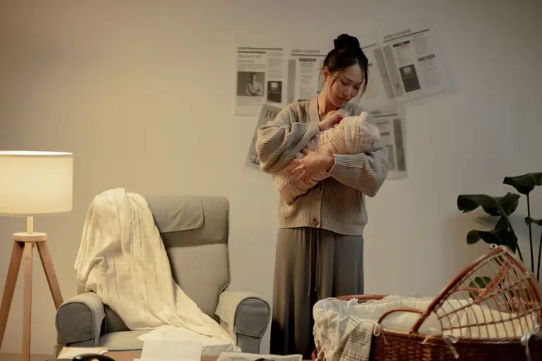 A mother lovingly cradles her newborn in a cozy living room, evoking warmth and care.