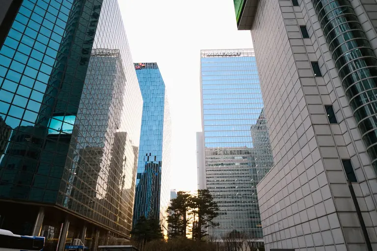 Urban cityscape featuring modern skyscrapers with reflective glass facades at sunset.