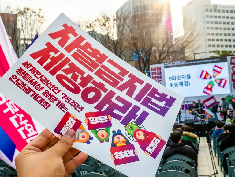 A person holding up a sign in front of a crowd