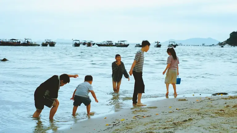 A group of people standing on top of a sandy beach
