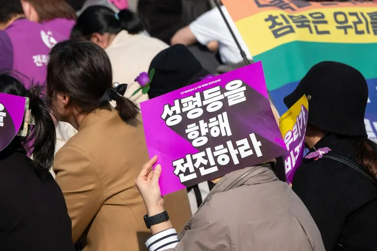 A group of people holding signs and wearing masks