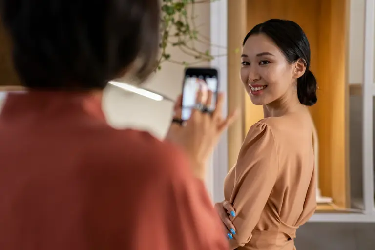Asian woman posing in a beige dress during a fashion photo shoot indoors.